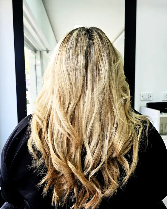 Cabello largo rubio con raíz más oscura, mechas y acabado con ondas