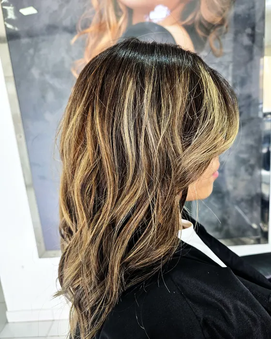 Cabello largo de base oscura con mechas claras y acabado ondulado