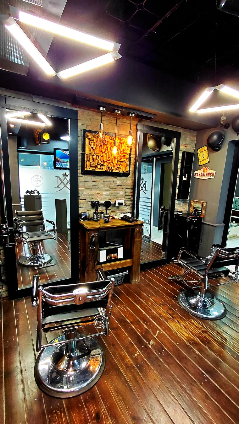 Le Club: sillón de barbero cromado, madera y luces cálidas